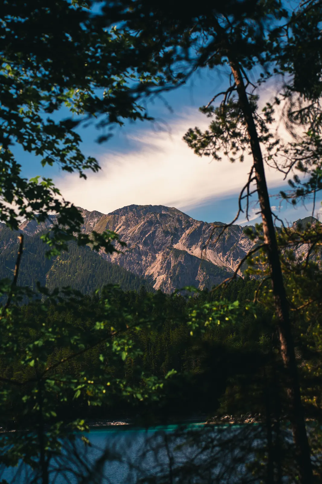 Alpine lake and sunlit mountains framed by trees
