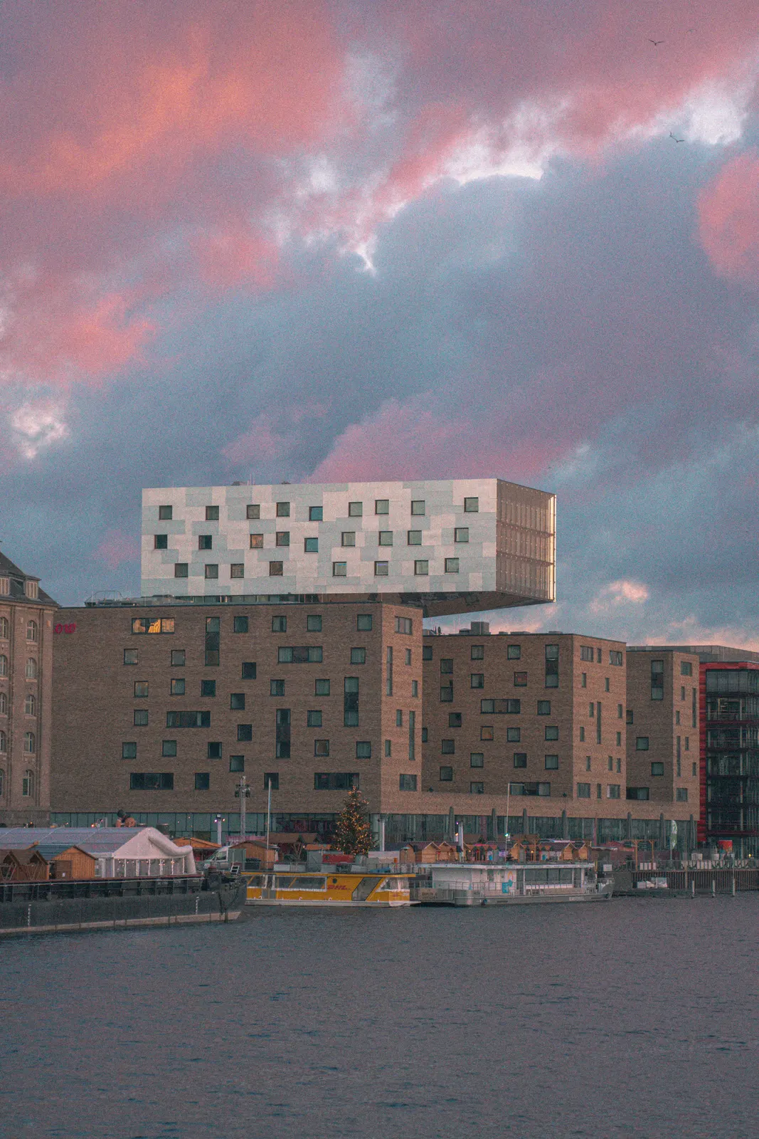 Modern riverside architecture under a pink sunset