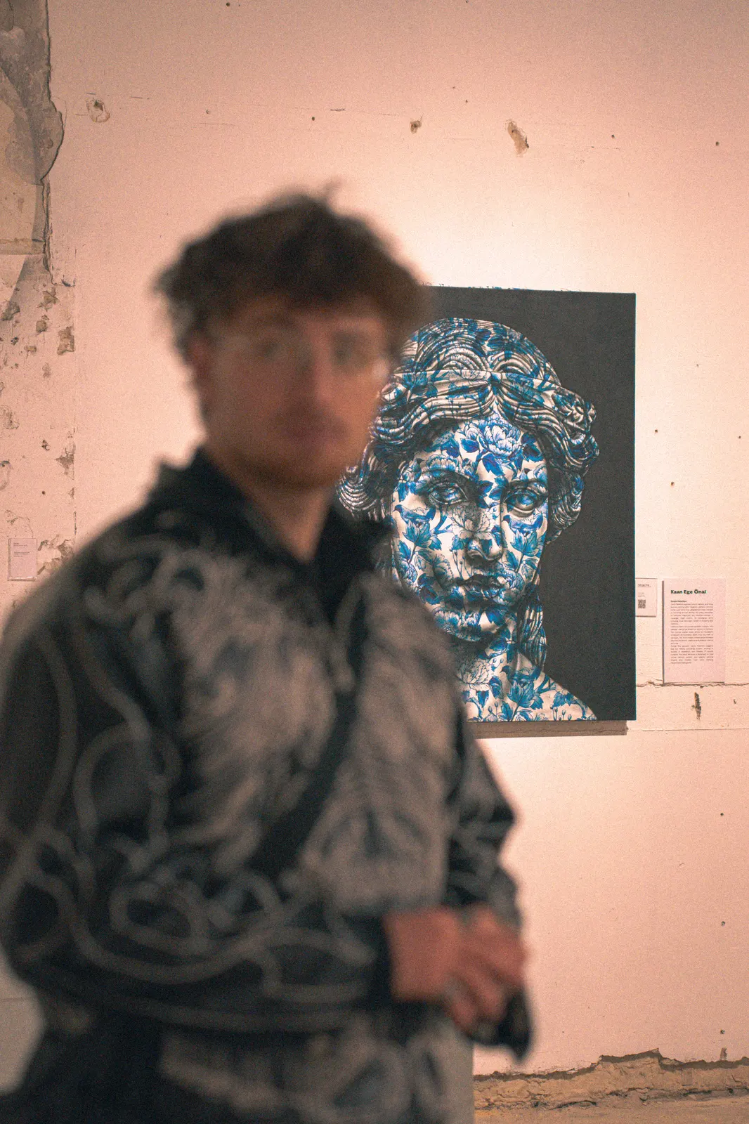 Exhibition visitor in front of a blue ceramic-pattern portrait
